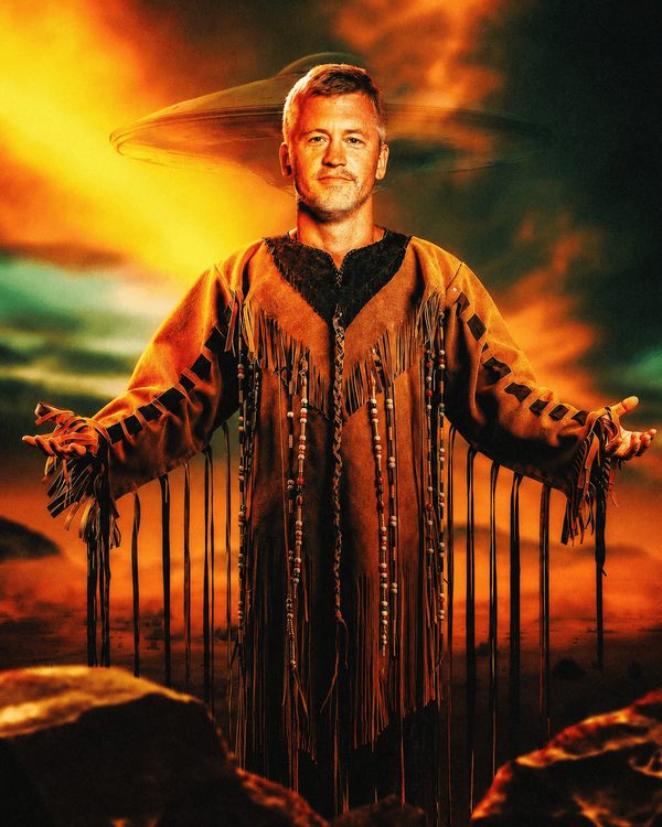 Matt McCusker in ceremonial fringe beneath a spacecraft